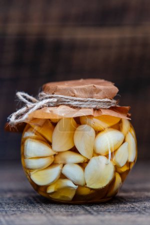 Foto de Cortar los dientes de ajo en rodajas de miel en frasco de vidrio, de cerca. Ajo infundido de miel - Imagen libre de derechos
