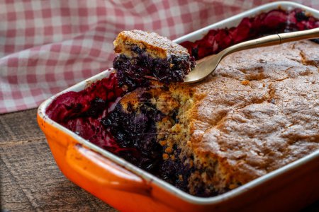 Photo for Fresh baked blueberry cobbler in a baking dish with fork. Homemade berry cobbler, close up - Royalty Free Image