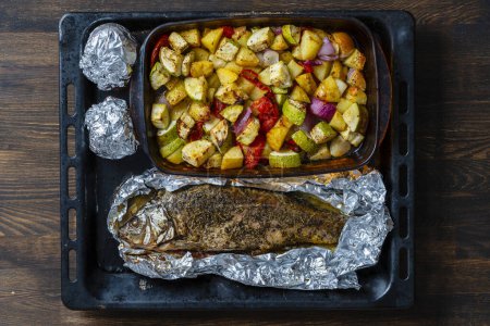 Téléchargez les photos : Mélanger les légumes cuits au four avec le poisson sur une plaque à pâtisserie, fermer, vue sur le dessus - en image libre de droit