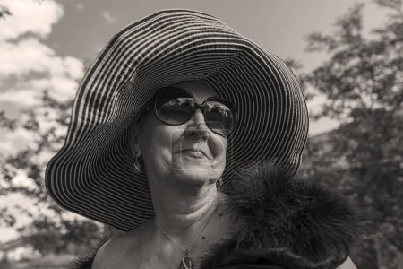 Photo for Portrait of a happy elderly woman 65 - 70 years old in a straw hat on the background of nature, close up. Black and white - Royalty Free Image