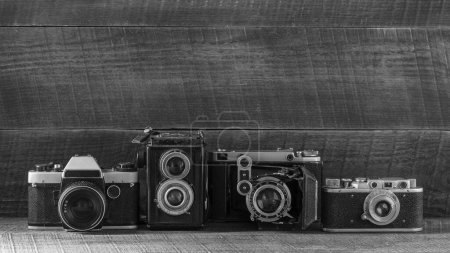 Foto de Conjunto de cámara de película vintage de los tiempos de la URSS sobre un fondo de madera, cerca, espacio de copia. Línea de viejas cámaras retro. Blanco y negro - Imagen libre de derechos