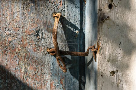 Foto de Gancho de puerta muy oxidado cerrando una puerta de madera, de cerca. Una vieja puerta de madera cerrada con un gancho oxidado igualmente viejo. Fondo vintage - Imagen libre de derechos