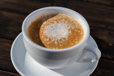 Téléchargez les photos : Mousse épaisse de cappuccino de café chaud sur table en bois, fermer. Cappuccino en mousse de lait, latte - en image libre de droit
