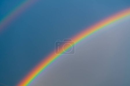 Téléchargez les photos : Double, beau, multicolore arc-en-ciel sur ciel bleu après une averse d'été - en image libre de droit