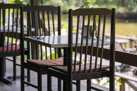 Téléchargez les photos : Chaises et table en bois sur la cour arrière dans un café tropical près du lac avec une belle vue sur l'île de Bornéo, Malaisie, gros plan - en image libre de droit