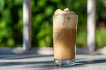 Photo for Glass of coffee with ice cream on the windowsill next to the window. Cold summer drink. Close up - Royalty Free Image
