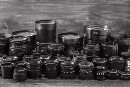 Photo for A lot of vintage camera lenses from the times of the USSR on a wooden background, close up. Black and white - Royalty Free Image
