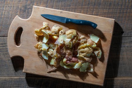 Téléchargez les photos : Pelure de pomme de terre bouillie sur une planche à découper en bois avec un couteau. Gros plan, vue du dessus. Peau de pomme de terre. Pommes de terre ingrédient de déchets organiques - en image libre de droit