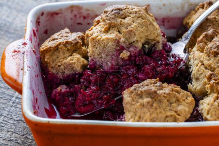 Photo for Fresh baked raspberries cobbler in a baking dish with fork. Homemade berry cobbler, close up - Royalty Free Image