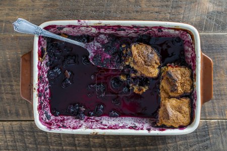 Photo for The last pieces of leftover blueberry cobbler in a ceramic baking dish, close up, top view - Royalty Free Image