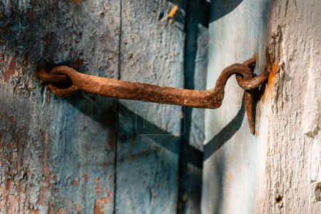 Photo for Very rusty door hook closing a wooden door, close up. An old wooden gate locked with an equally old rusty hook . Vintage background - Royalty Free Image