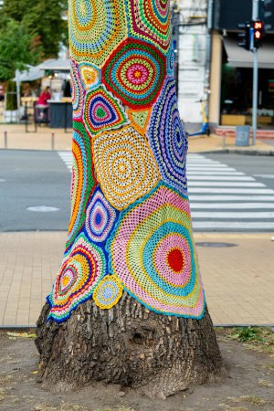 Téléchargez les photos : Tricot au crochet coloré sur un tronc d'arbre à Kiev, Ukraine. Le street art porte des noms différents, tricot graffiti, bombardement de fils. Fond abstrait de tapis tricotés avec un motif de cercles multicolores - en image libre de droit