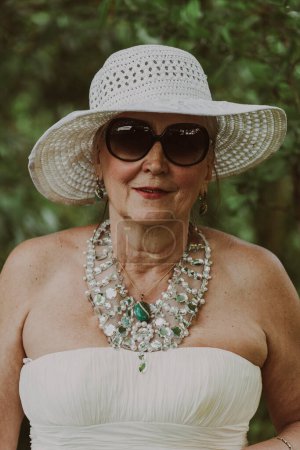 Foto de Retrato de una anciana feliz de 65 a 70 años en un sombrero de paja en el fondo de la naturaleza, de cerca - Imagen libre de derechos