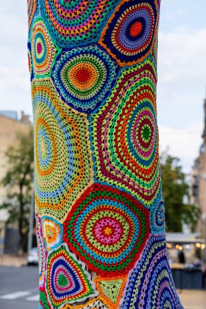 Téléchargez les photos : Tricot au crochet coloré sur un tronc d'arbre à Kiev, Ukraine. Le street art porte des noms différents, tricot graffiti, bombardement de fils. Fond abstrait de tapis tricotés avec un motif de cercles multicolores - en image libre de droit
