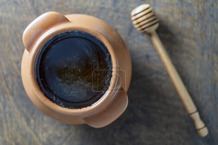 Foto de Miel cruda en un tarro de cerámica y cazo de miel en el fondo de madera, de cerca, vista superior - Imagen libre de derechos