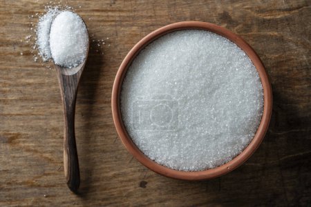 Foto de Azúcar blanco en una olla de barro y cuchara de madera, vista superior, primer plano - Imagen libre de derechos