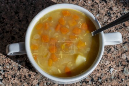 Foto de Vegetariana sopa de guisantes partida amarilla con papa, cebolla, zanahoria y especias en tazón blanco, primer plano - Imagen libre de derechos