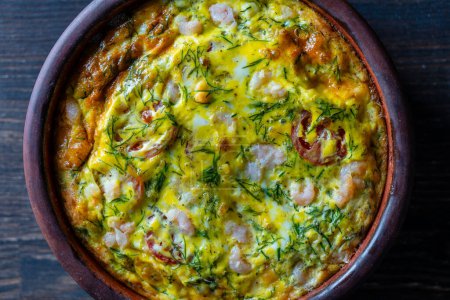 Photo for Ceramic bowl with vegetable frittata, simple food. Frittata with egg, tomato, pepper, onion, shrimps and cheese on wooden table, close up, top view. Italian egg omelette - Royalty Free Image