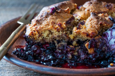 Photo for Slice of fresh baked blueberry cobbler on plate with fork. Homemade berry cobbler, close up - Royalty Free Image
