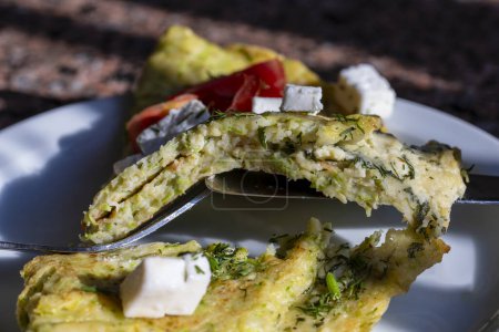 Foto de Panqueques de calabacín rellenos de queso y hierbas en plato blanco, de cerca. Pastel con calabacín, queso y hierbas en la mesa - Imagen libre de derechos