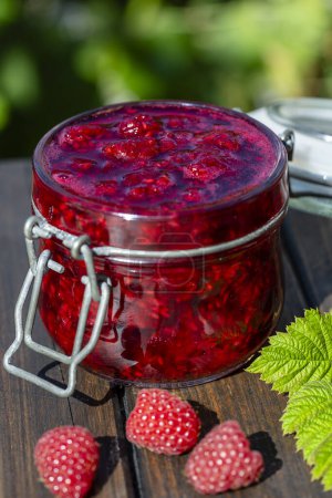 Photo for Red raspberry jam and fresh raspberry, outdoors near garden. Rustic style, close up - Royalty Free Image