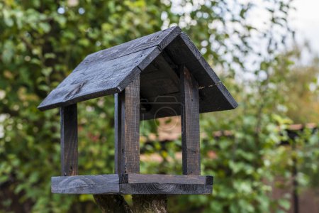 Photo for Wooden bird feeder in the form of a house on an autumn garden, close up - Royalty Free Image