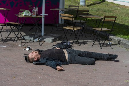 Photo for Kyiv, Ukraine - September 22, 2023 : Drunk homeless man lying on the sidewalk after drinking a bottle of vodka - Royalty Free Image