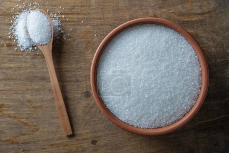 Photo for White sugar in a clay pot and wooden spoon, top view, close up - Royalty Free Image