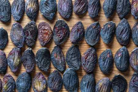 Photo for Sun dried pitted plums on a wooden table, close up, top view. Background and texture of dried raw plums - Royalty Free Image