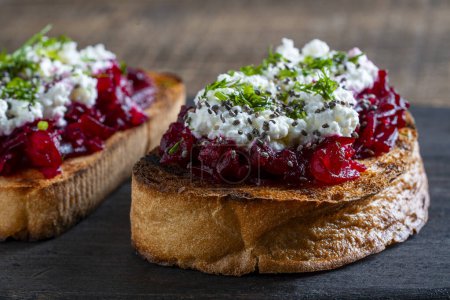 Photo for Toast from a slice of bread with white cream cheese, stewed beetroot pulp, seeds and green dill on wooden board. Delicious breakfast on morning. Close up - Royalty Free Image