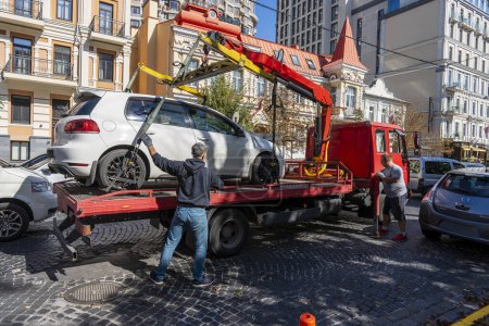 Photo for Kyiv, Ukraine - September 19, 2023 : Tow truck takes away a wrongly parked car on central street in Kyiv, Ukraine. Violation of the traffic rules. Evacuating a car from a city street - Royalty Free Image