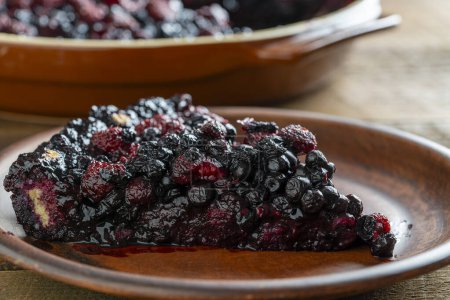 Photo for Slice of fresh baked blueberry and raspberry pie in a ceramic dish on the table, close up - Royalty Free Image