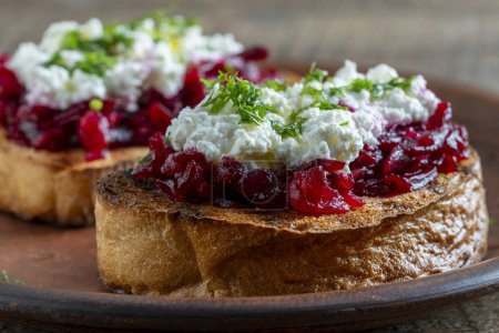 Photo for Toast from a slice of bread with white cream cheese, stewed beetroot pulp, seeds and green dill on wooden board. Delicious breakfast on morning. Close up - Royalty Free Image