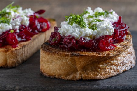 Photo for Toast from a slice of bread with white cream cheese, stewed beetroot pulp, seeds and green dill on wooden board. Delicious breakfast on morning - Royalty Free Image