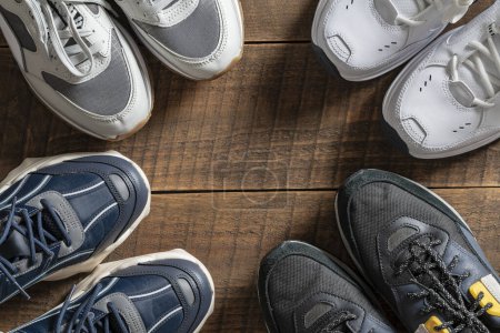 Photo for Four pairs of various sneakers on a wooden background, close up, top view, copy space - Royalty Free Image