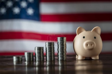 Photo for Pink piggy bank and money towers on the American flag background, close up, copy space. Finance, business, investment and money saving concept - Royalty Free Image