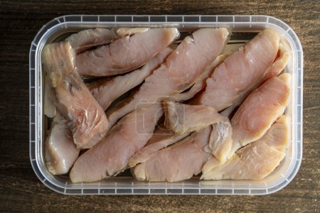 Foto de Trozos de pescado de salmón en salsa de aceite en una caja de plástico, de cerca, vista superior - Imagen libre de derechos