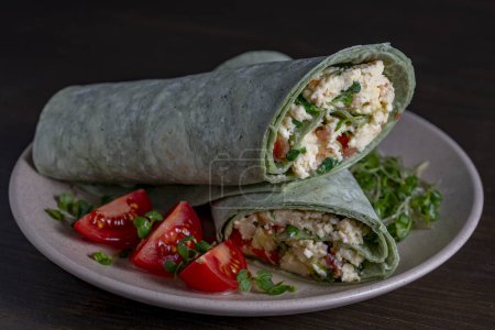 Photo for Burrito wraps with scrambled egg omelet and vegetables in green pita bread in plate. Close up - Royalty Free Image