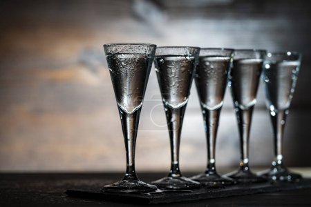 Photo for Selective focus of five shot glasses of cold vodka on wooden table, close up - Royalty Free Image