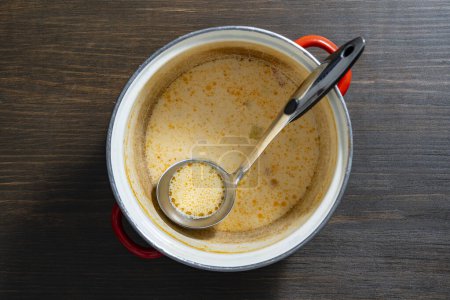 Téléchargez les photos : Reste de soupe de poisson à la crème dans une casserole avec une louche sur une table en bois, gros plan, vue sur le dessus - en image libre de droit