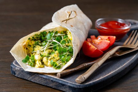 Photo for Homemade burrito wraps with scrambled egg omelet and microgreens for healthy breakfast on wooden board, close up - Royalty Free Image