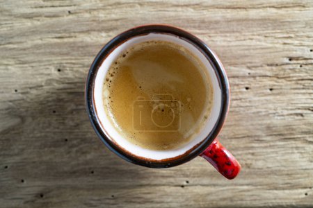Téléchargez les photos : Vue du dessus une tasse de café expresso rouge sur fond de table en bois le matin, gros plan - en image libre de droit