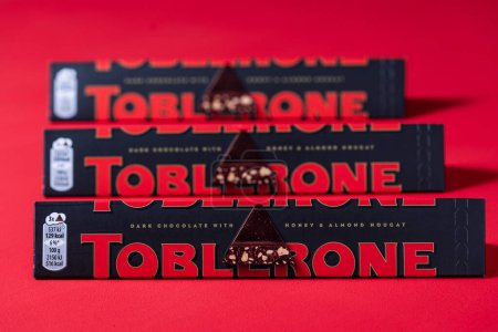 Photo for Kyiv, Ukraine - Mar 20, 2024 : Toblerone Swiss Dark Chocolate with Honey and Almond Nougat on a red background, close up. Toblerone is a Swiss Chocolate bar of Mondelez International - Royalty Free Image