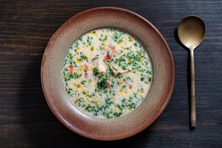 Photo for Fresh creamy salmon fish soup with potatoes, carrots, peppers and onions in a ceramic plate on a wooden table, close up, top view. A delicious dinner consists of fish soup with salmon - Royalty Free Image