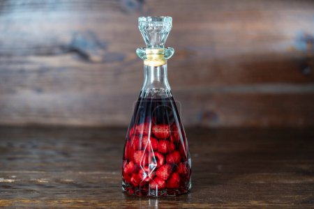 Foto de Botella de vidrio de licor de frambuesa rojo casero sobre un fondo de madera, de cerca. concepto de bebidas alcohólicas de bayas - Imagen libre de derechos