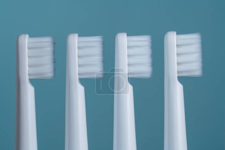 Téléchargez les photos : Quatre brosses à dents en plastique blanc sur fond bleu, gros plan - en image libre de droit