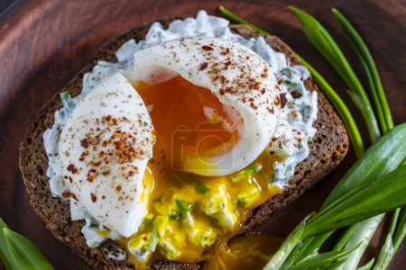 Photo for Delicious sandwich with bread, salad of green wild garlic, soft-boiled egg and sour cream on plate, close up - Royalty Free Image