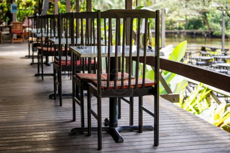 Téléchargez les photos : Chaises et table en bois sur la cour arrière dans un café tropical près du lac avec une belle vue sur l'île de Bornéo, Malaisie, gros plan - en image libre de droit