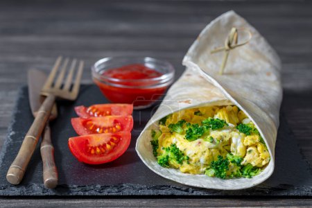 Foto de Burrito casero envuelve con tortilla de huevo revuelto y microgreens para un desayuno saludable en tablero de madera, de cerca - Imagen libre de derechos