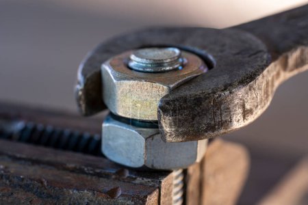 Photo for Loosening the nut using a wrench and a vise. Using old spanner wrench and clamp to remove nut from bolt, close up - Royalty Free Image